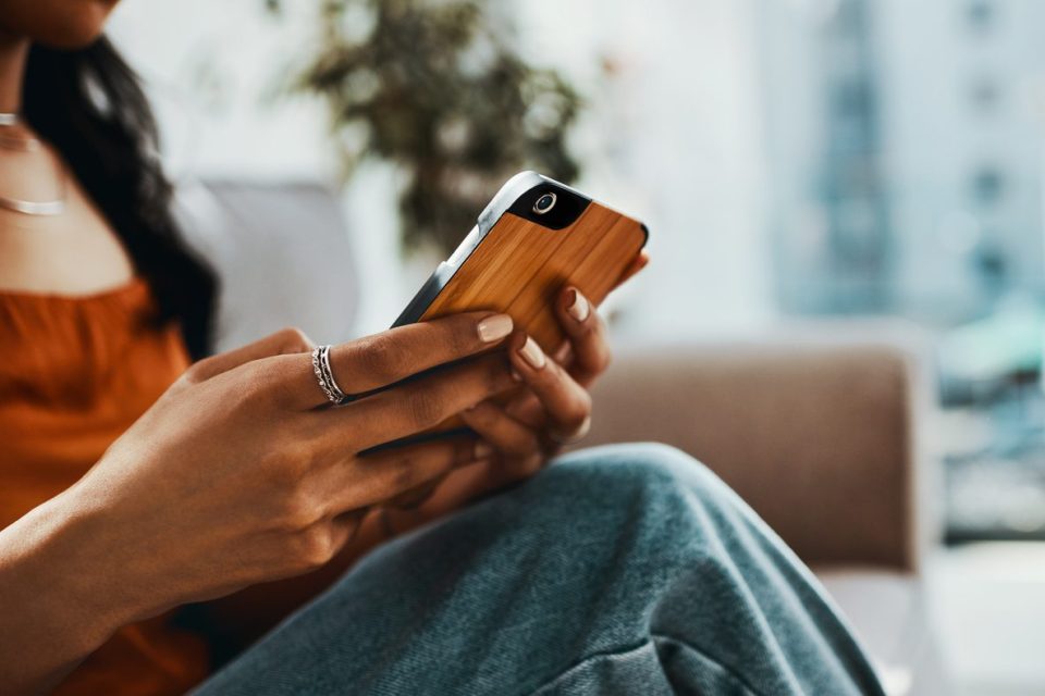Cropped shot of a woman using a smartphone while relaxing on the sofa at home