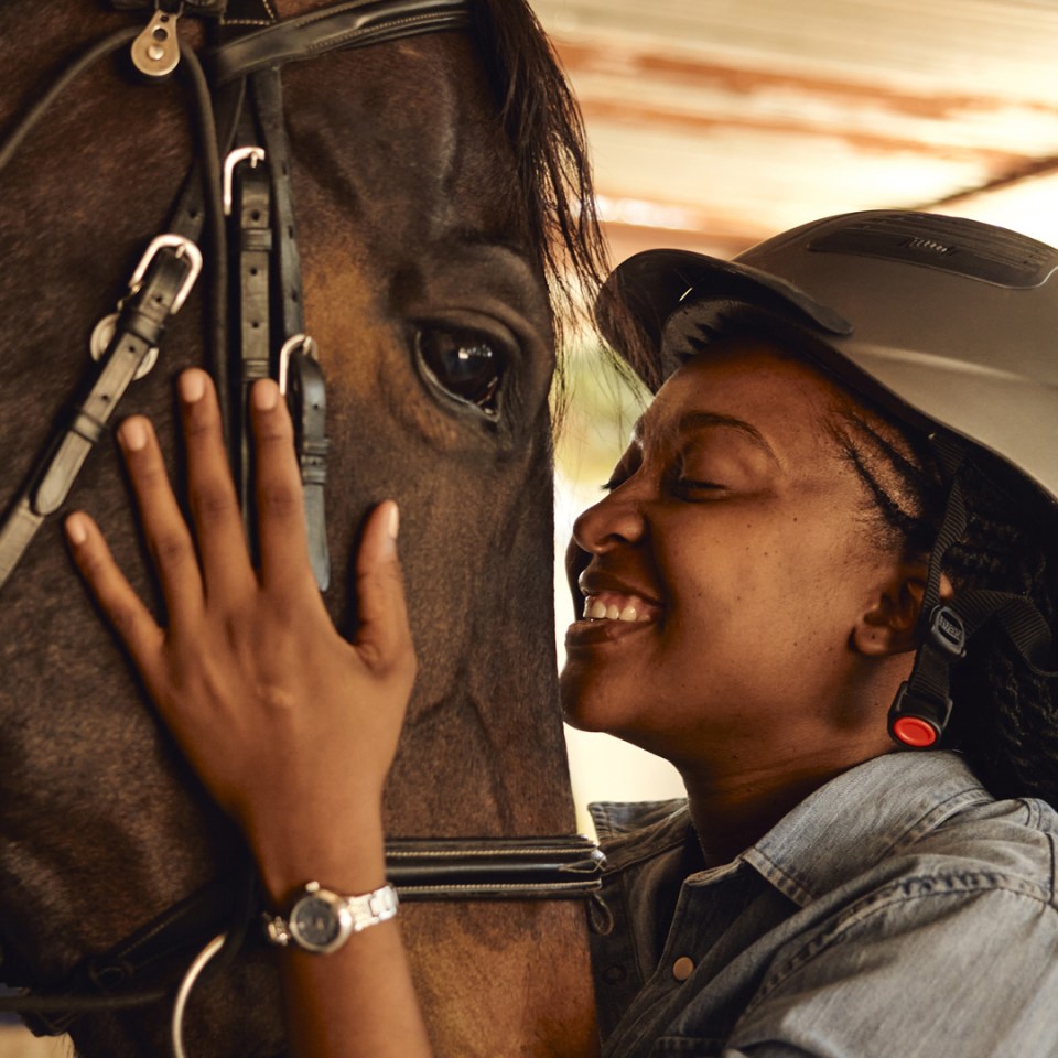 Une femme étreignant un cheval dans une écurie.