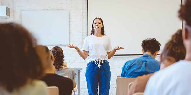 Une enseignante debout devant une classe pour donner un cours.