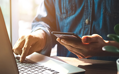 Un homme connecté avec un ordinateur portable et un smartphone.