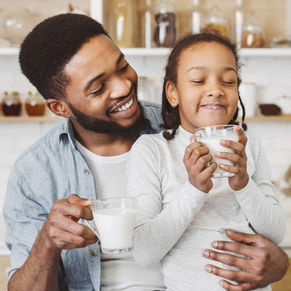 Un père et sa fille dégustent un verre de lait ensemble.